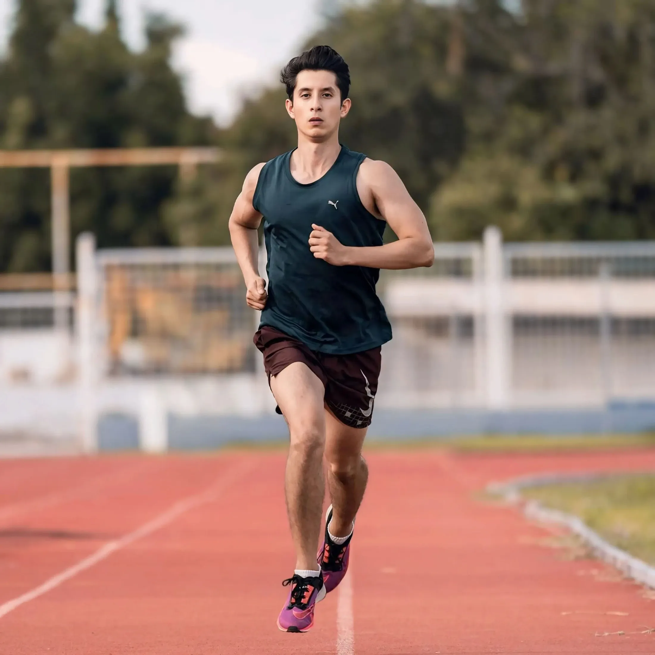 Açık hava atletizm pistinde koşu antrenmanı yapan genç sporcu