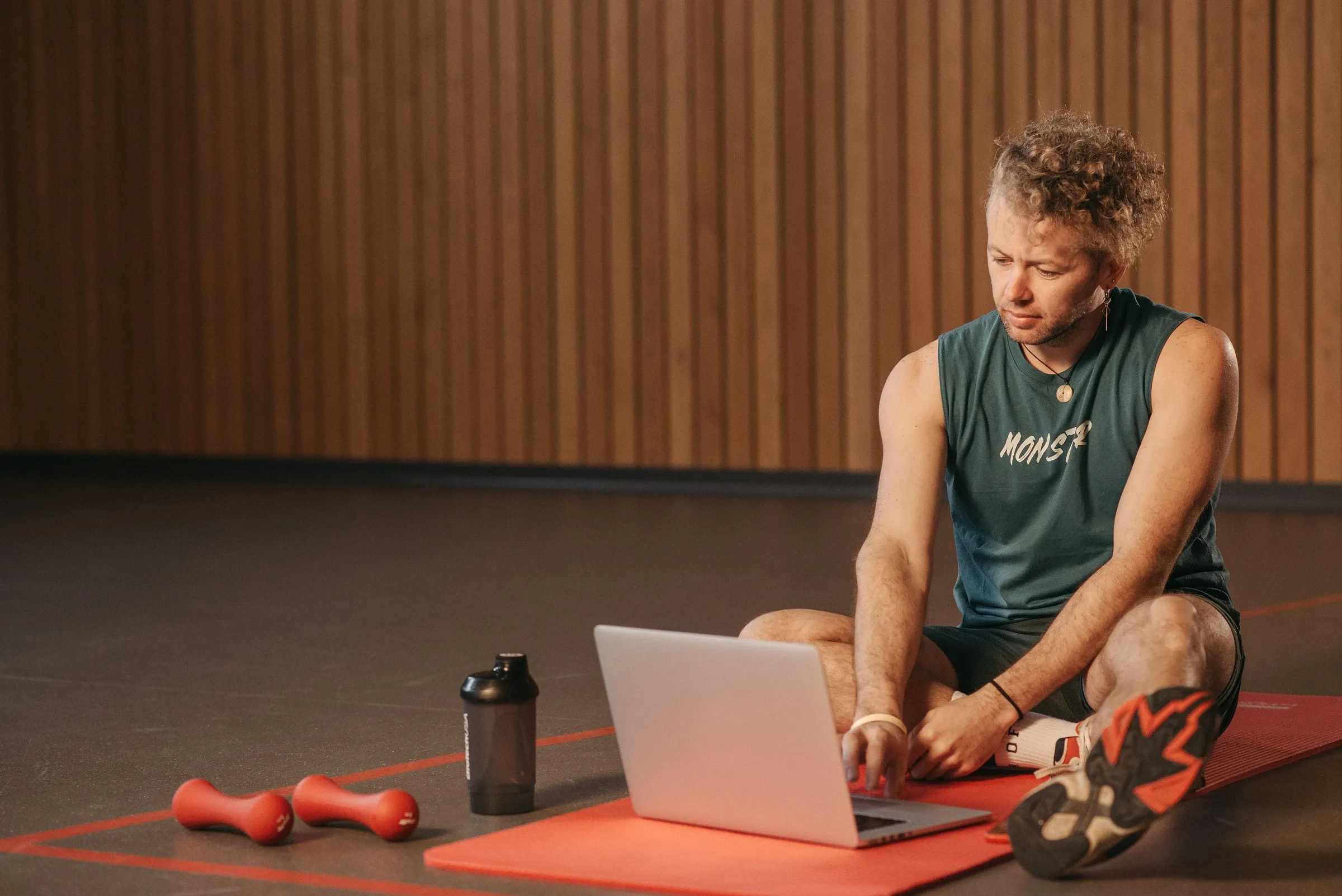 Antrenman matı üzerinde dizüstü bilgisayardan online fitness programını takip eden sporcu